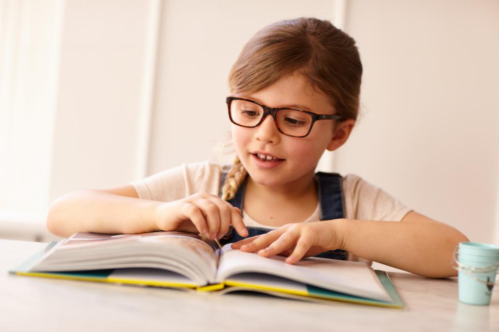 Девочка в очках за чтением книги